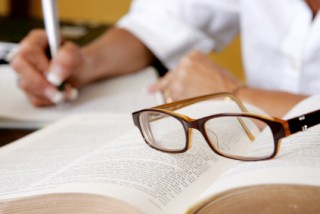 researcher writing with glasses
